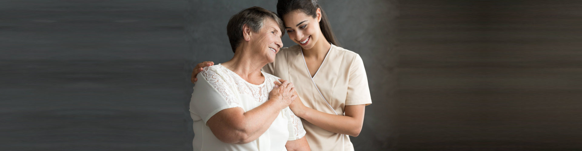 elderly and caregiver hugging